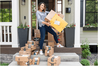 joanie holding amazon boxes on a porch