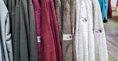 collection of north face fleece zip up jackets hanging on a rack