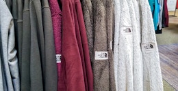 collection of north face fleece zip up jackets hanging on a rack