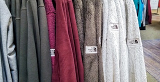 collection of north face fleece zip up jackets hanging on a rack