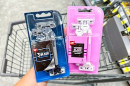 person holding 2 packs of disposable razors over a cart