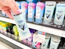 hand holding a bottle of deodorant in front of a store shelf