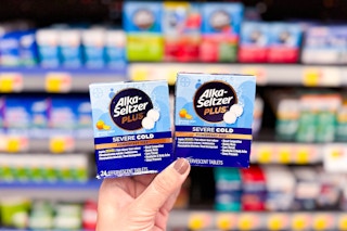 person holding 2 boxes of alka seltzer cold medicine