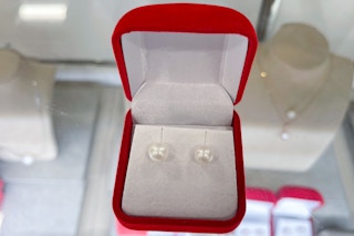 Macy's Bella de mar freshwater pearl earrings in a box on a glass counter.