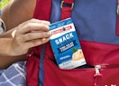 a hand putting a tuna kit in a red backpack