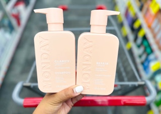 person holding two bottles of Monday hair care products