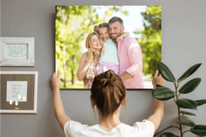 A woman hangs a large print in a room 