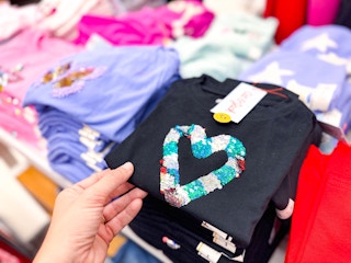 hand grabbing a cat & jack graphic tee off a target shelf