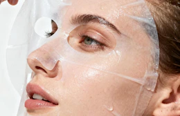 a person pulling a sheet mask off their face