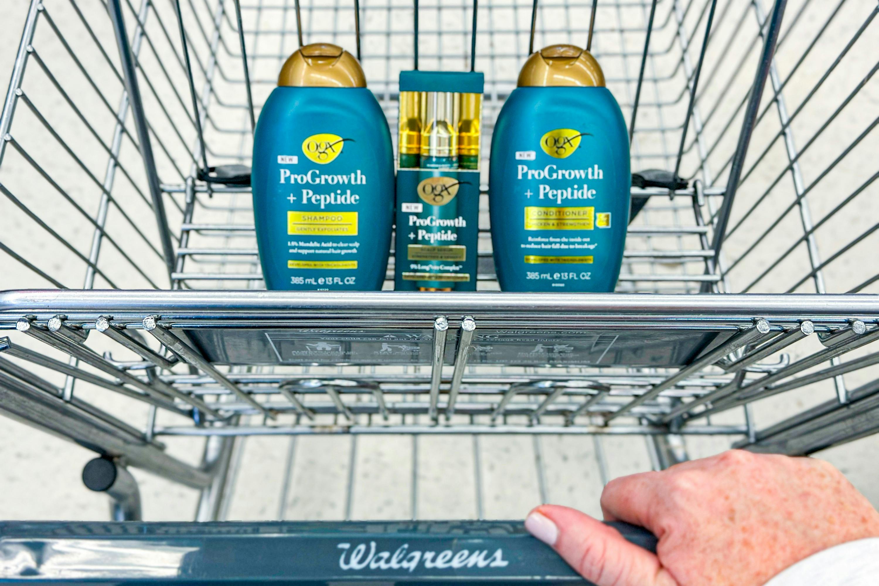 hand pushing a walgreens shopping cart with OGX progrowth hair care products