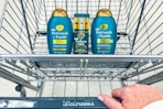 hand pushing a walgreens shopping cart with OGX progrowth hair care products