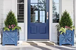 Lifestyle image of two Vitalismo Artificial Cedar Topiary Trees in a front porch setting outdoors