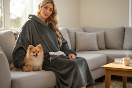 a woman sitting on a couch next to a pomeranian