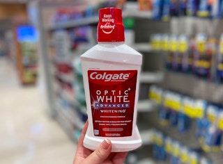 a hand holding a bottle of mouthwash in a store aisle