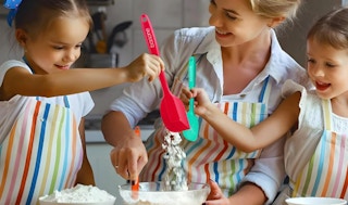 a family mixing flour in a bowl with spatulas 