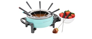 a bowl of strawberries next to chocolate fondue pot