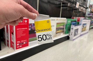 hand holding a 50% target clearance tag in front of TVs