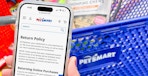 Someone holding a phone displaying the Petsmart return policy in front of a Petsmart shopping cart