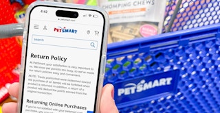 Someone holding a phone displaying the Petsmart return policy in front of a Petsmart shopping cart