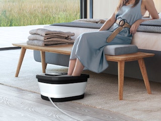 a person sitting on a bench using a foot spa