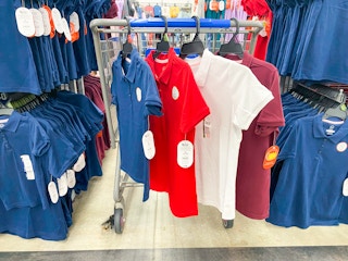 four kids uniform polo shirts hanging on walmart cart