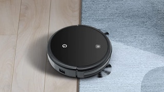 A Yeedi robotic vacuum on a carpet and hardwood floor.