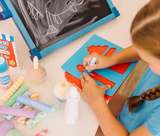 A child drawing with the chalk and stencil set on a table
