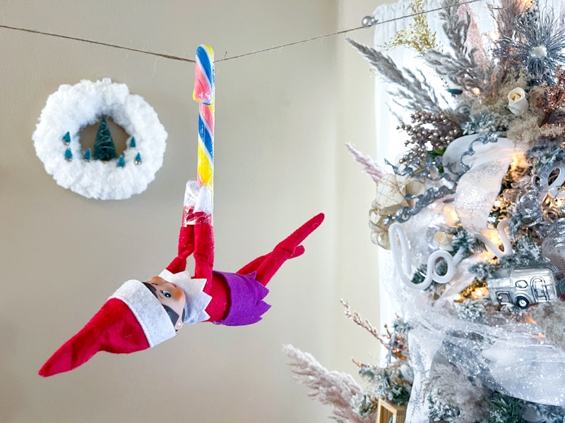 elf on the shelf riding candy cane zipline through living room