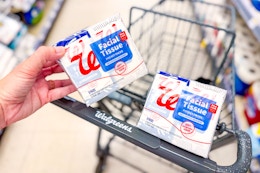person placing a box of tissues in a cart