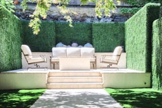 lifestyle image of a patio furniture set outdoors surrounded by greenery