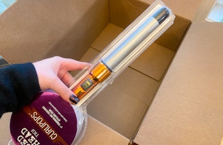 hand holding bed head tigi curlipops curling iron wand over a box