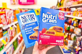 person holding 2 boxes of kelloggs nutri-grain bars in an aisle