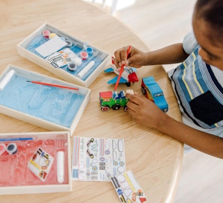 a kid painting a wooden car toy