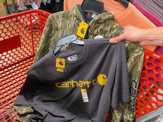 A man putting a Carhartt shirt and hoodie into a Tractor Supply cart.