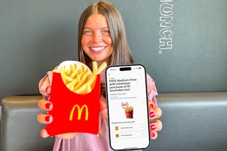 a person holding up fries and a phone with the mcdonalds app on it