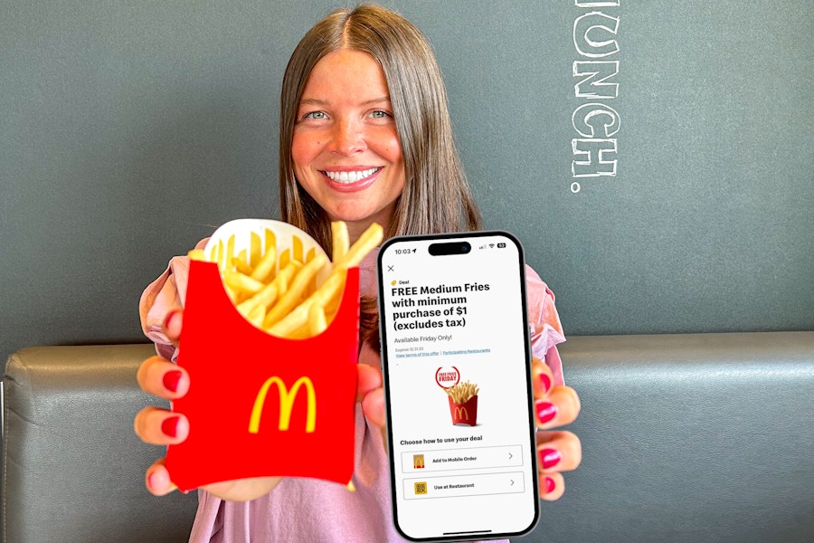 a person holding up fries and a phone with the mcdonalds app on it