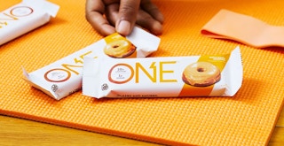 hand grabbing a one protein bar on an orange background