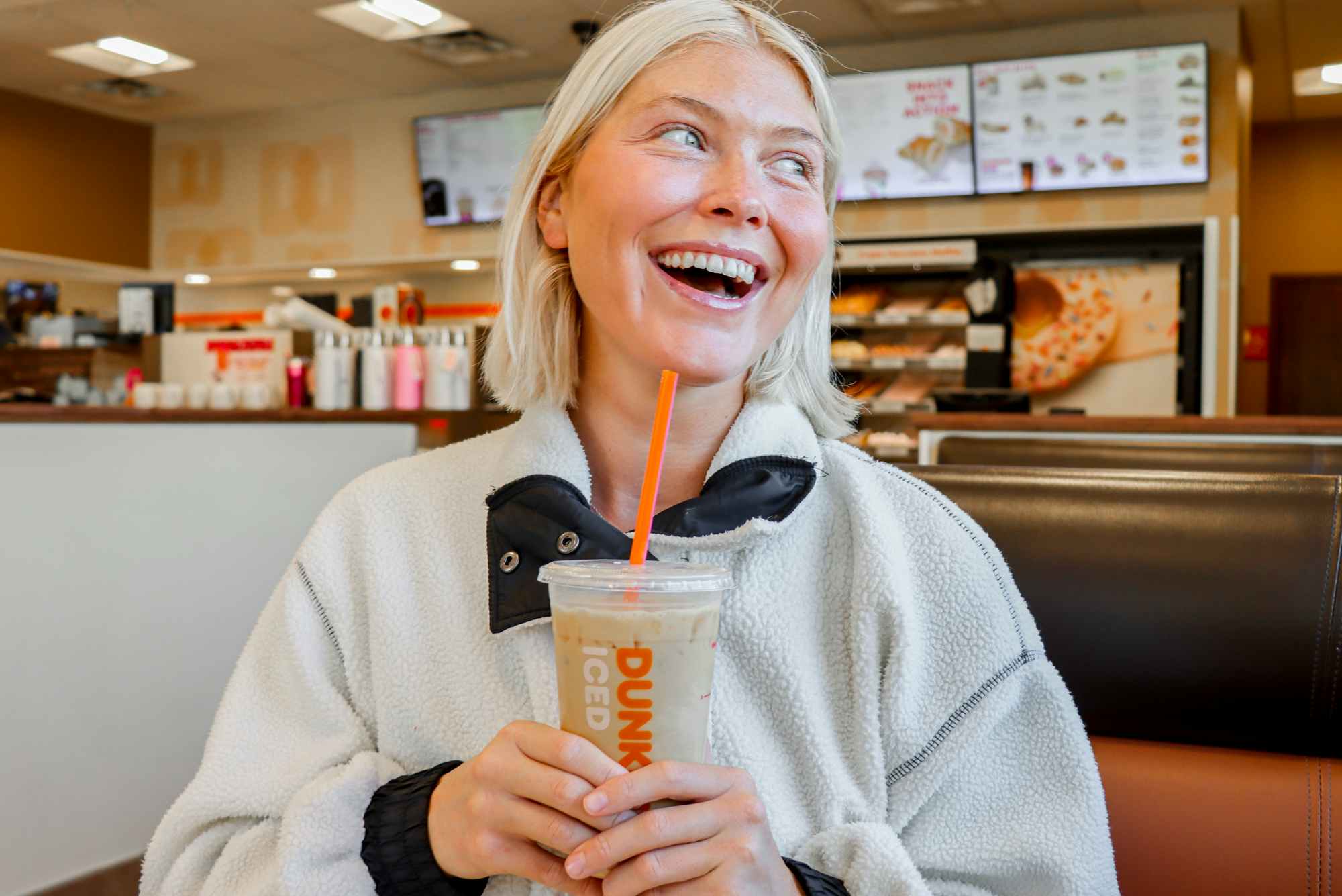 a person posing with an iced coffee at dunkin donuts