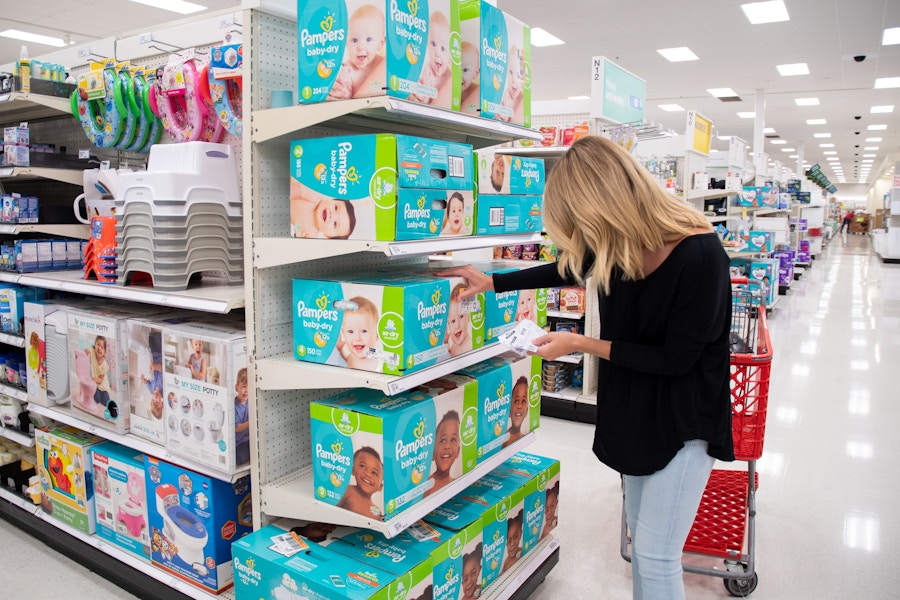 A woman shopping for Pampers diapers with coupons in Target.