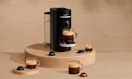 a Nepresso machine on a wooden display with pods and cups of coffee