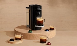 a Nepresso machine on a wooden display with pods and cups of coffee