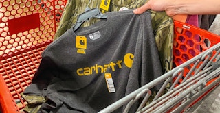 a person putting a Carhartt shirt and hoodie into a Tractor Supply cart.