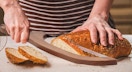 a person slicing a loaf of bread 