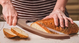 a person slicing a loaf of bread 