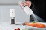 person using salt grinder on plate of food