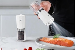 person using salt grinder on plate of food