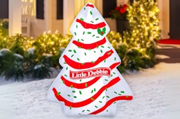 Lifestyle image of the Little Debbie Christmas inflatable outdoors in snow in front of house