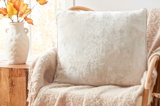 Lifestyle image of the Way to Celebrate crushed velvet throw pillow in a accent chair