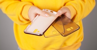 A person holding three empty phone cases