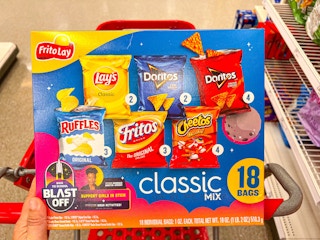 a person placing a frito lay variety pack into a target shopping cart